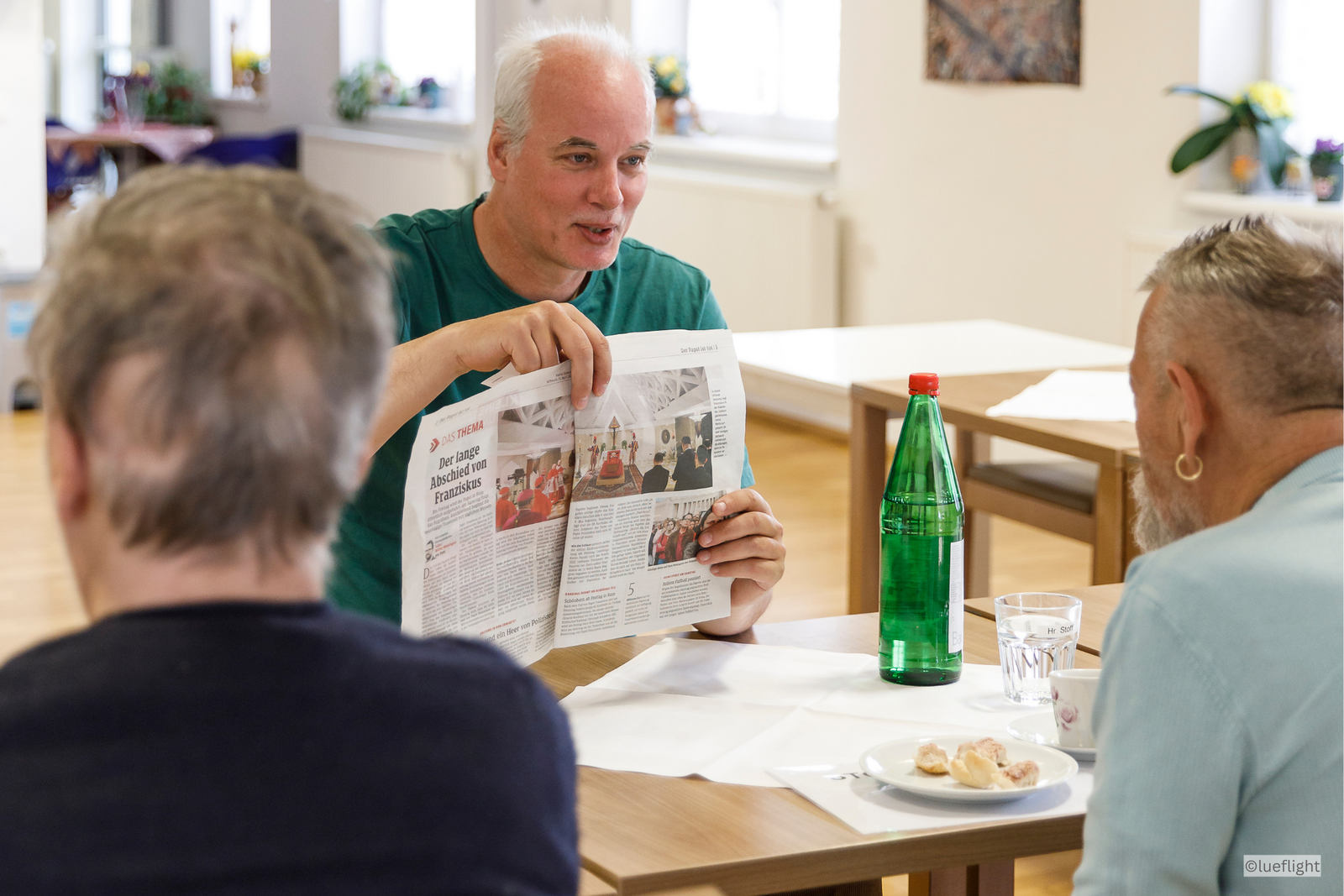 Ein Mitarbeiter und zwei Gäste beim Zeitunglesen