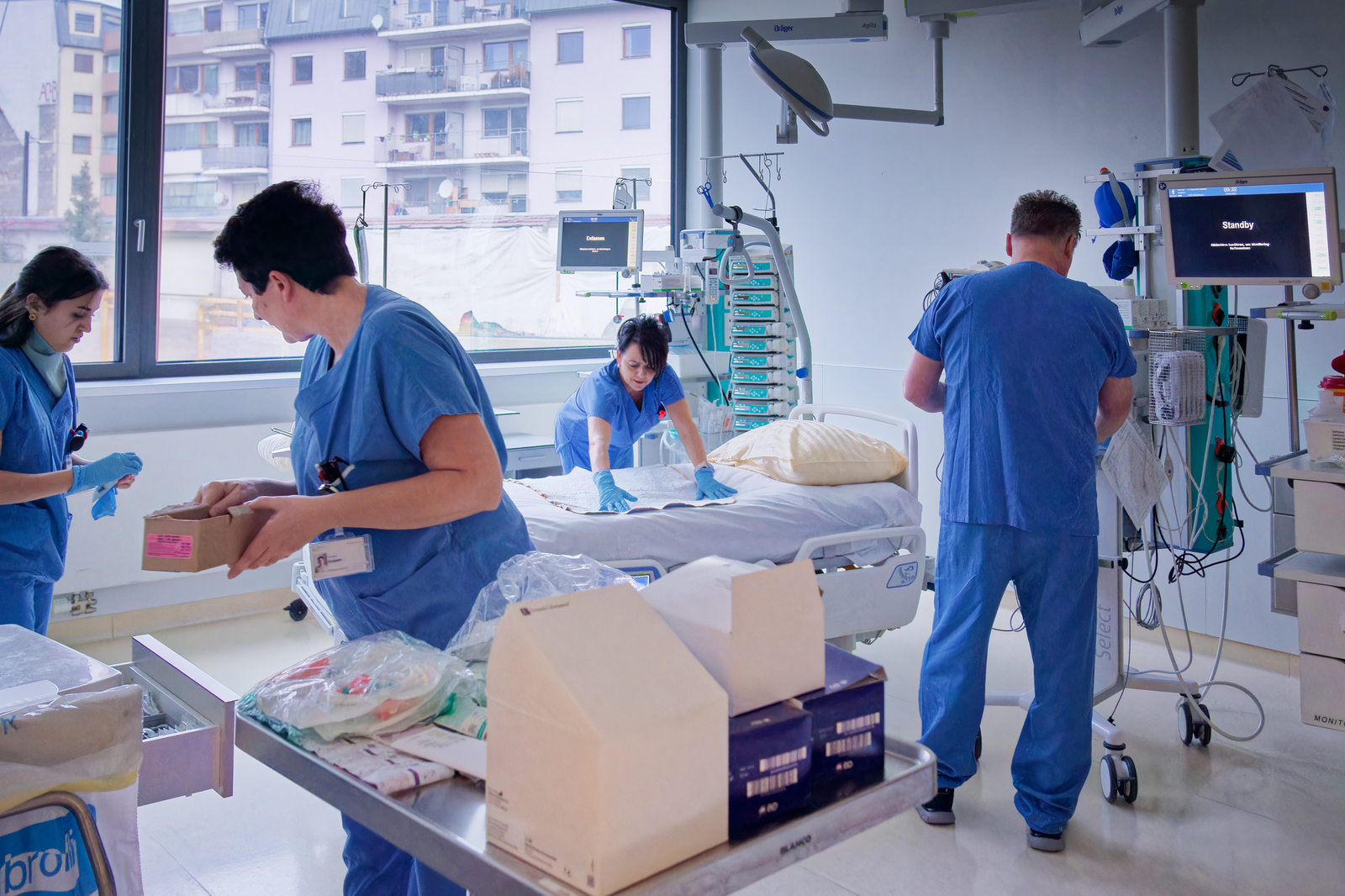 Pflegepersonen, die ein Zimmer auf der Intensivstation für die ankommenden Patient:innen vorbereiten.