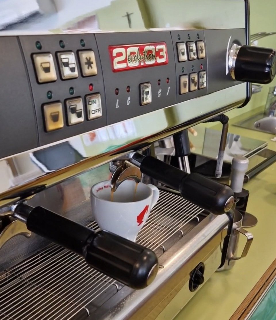 Kaffeemaschine, die gerade frischen Kaffe in eine Tasse laufen lässt.