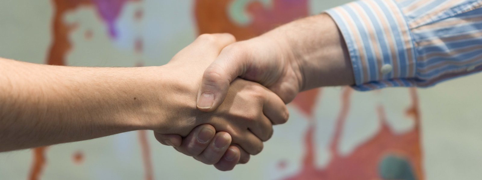 Zwei Personen geben sich die Hände. Im Hintergrund ein Bild der heiligen Elisabeth.