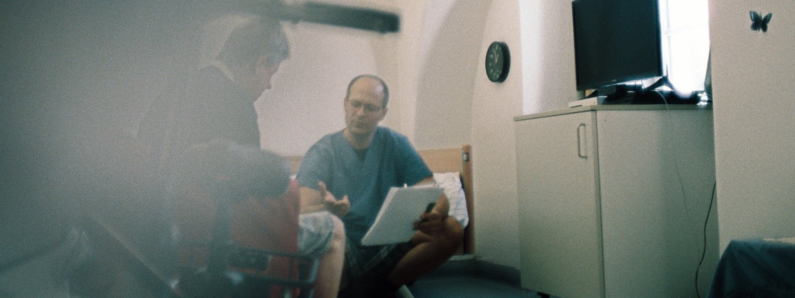 Zwei Männer sitzen auf der Bettkante und reden miteinander