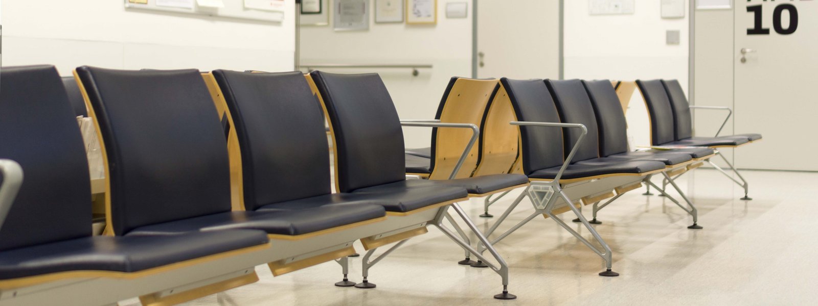 Sitzreihen aus Holz mit schwarzem Leder im Ambulanzgebäude