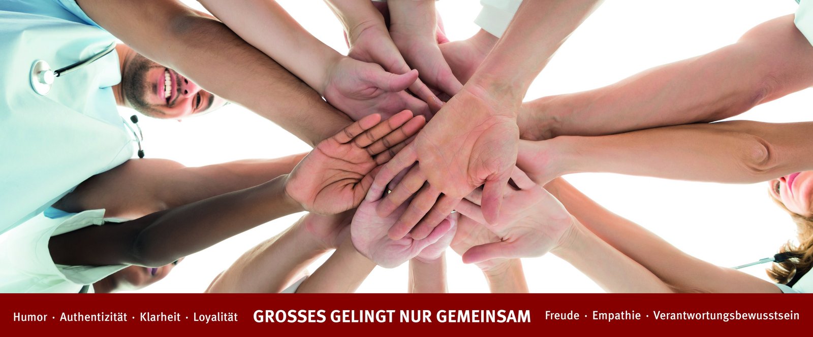 Hände die zusammengreifen, darunter die Wort: Humor, Authentizität, Loyalität, Freude, Empathie, Verantwortungsbewusstsein und Klarheit.